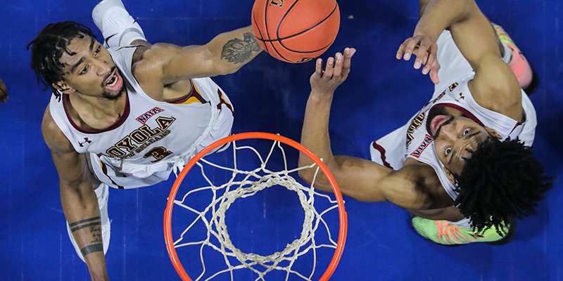 Two basketball players chasing a ball